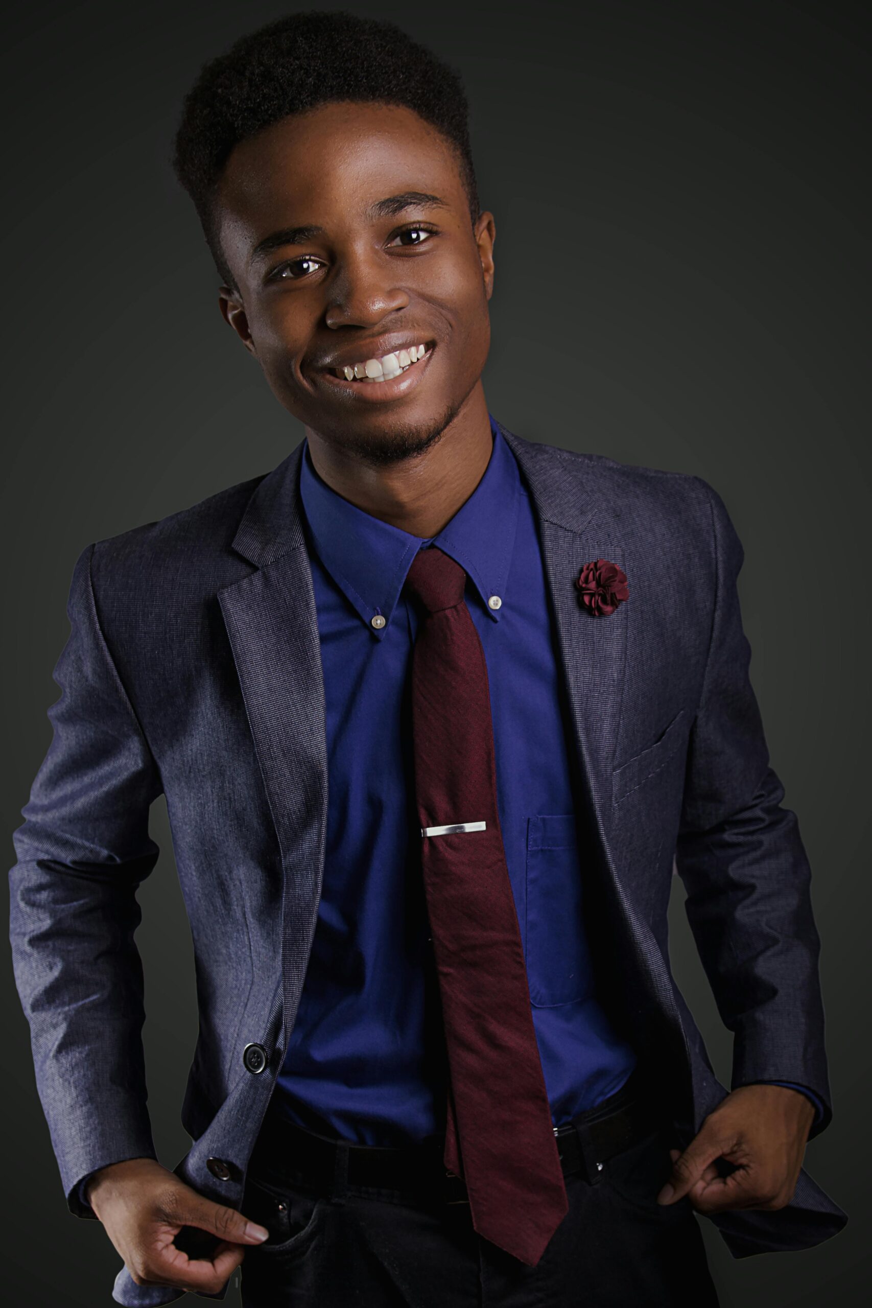 Portrait of a smiling young black man in a stylish suit with a confident pose.